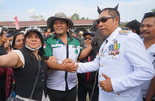 Bupati Tapanuli Utara, Dr. Jonius Taripar Parsaoran Hutabarat, menyapa ribuan penonton saat menghadiri Final Gebyar Taput XXIII Open Race Pordasi Cup 2025 di Gelanggang Pacuan Kuda Siborongborong, Minggu (17/8/2025).
