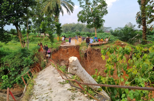 Warga mengambil resiko berjalan diatas jembatan Bah bolon yang ambruk (foto: Kabarnas)