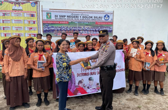Kapolsek Dolok Silau AKP Josia membagikan buku kepada pelajar dan masyarakat