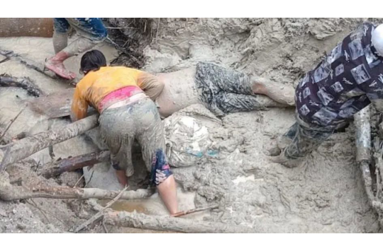 Istri korban (baju kuning) bersama warga mengevakuasi korban kecelakaan sepeda motor di lokasi jalan rusak dan berlumpur akibat longsor di Desa Parbuluan IV, Kabupaten Dairi, Sabtu (13/12/2025).