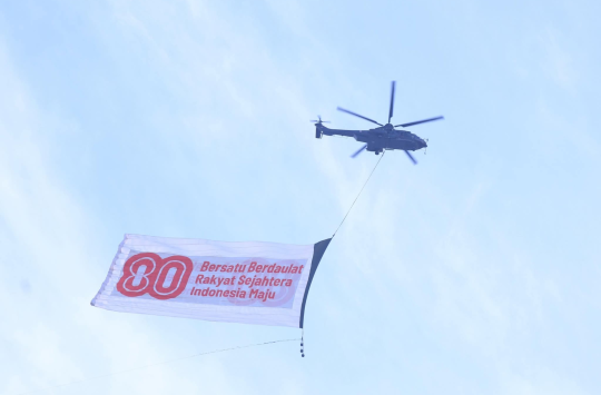 Helikopter EC‑725 Caracal Skadron Udara 8, membentangkan bendera bertema “Bersatu Berdaulat, Rakyat Sejahtera, Indonesia Maju”.