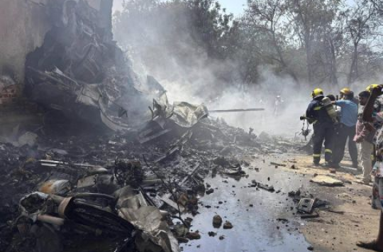 Asap tebal dan kobaran api membumbung dari puing-puing pesawat Air India yang jatuh di Ahmedabad, Kamis siang (12/6/2025). Tim penyelamat terlihat berjibaku di lokasi kejadian.